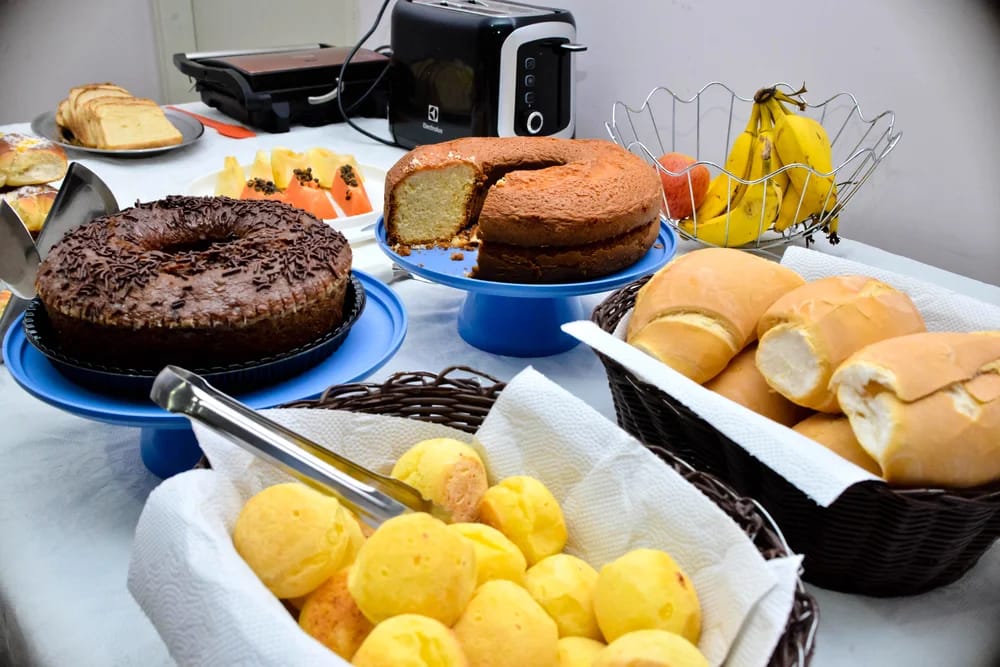 Mesa do café da manhã com bolos, pão de queijo, pães e frutas